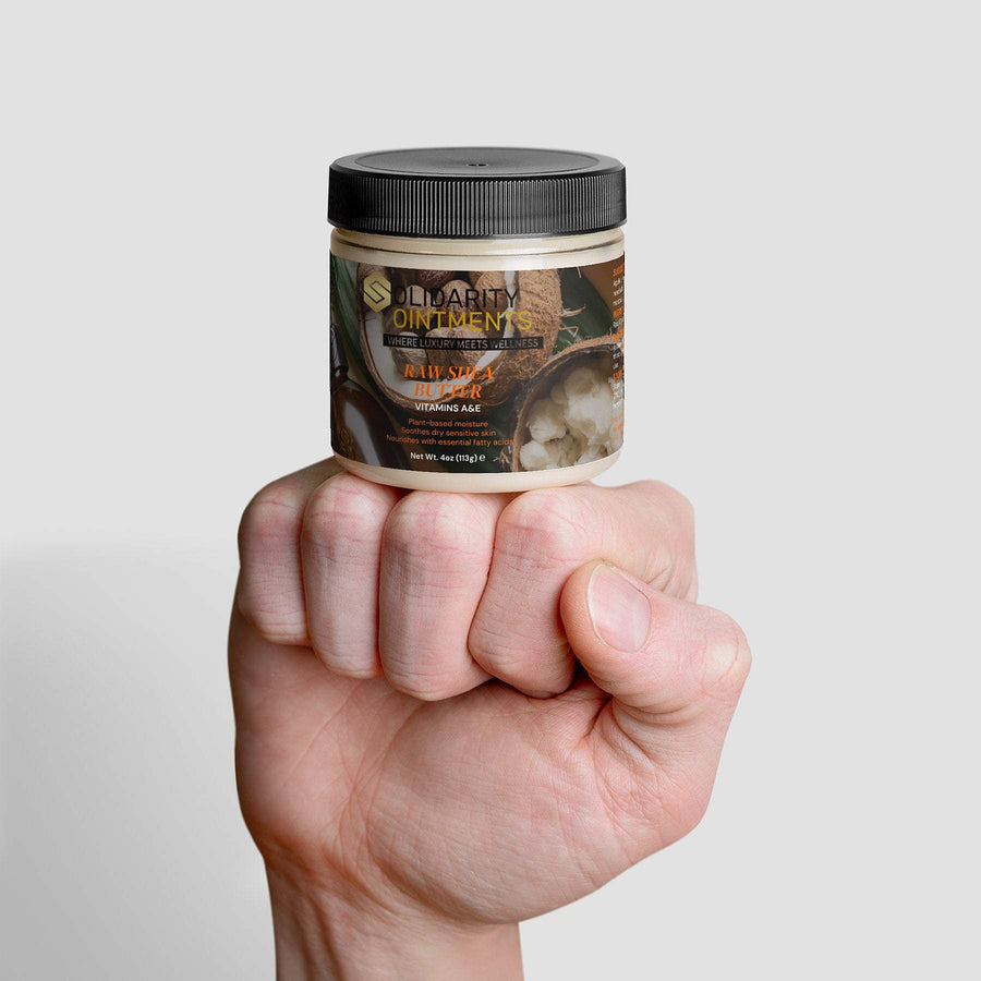 Organic raw shea butter jar held in a hand, providing rich moisture for skin and hair.