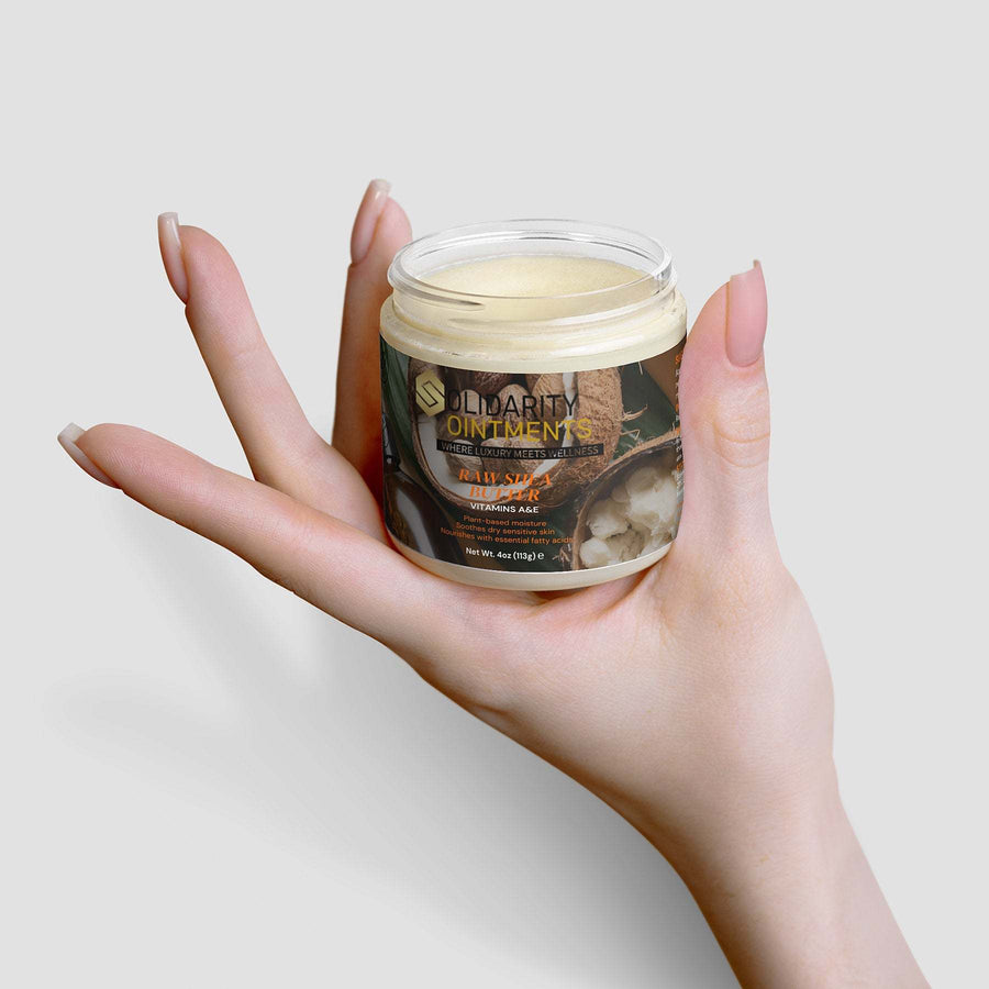 Hand holding a jar of raw shea butter for moisturizing skincare.