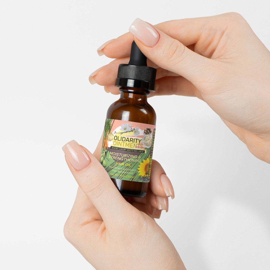 Moisturizing and strengthening hair oil in a brown glass bottle with a dropper, held in hand.