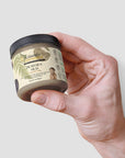 Jar of Dead Sea Mud held in hand, showcasing natural skincare product with mineral-rich formula for revitalizing skin.