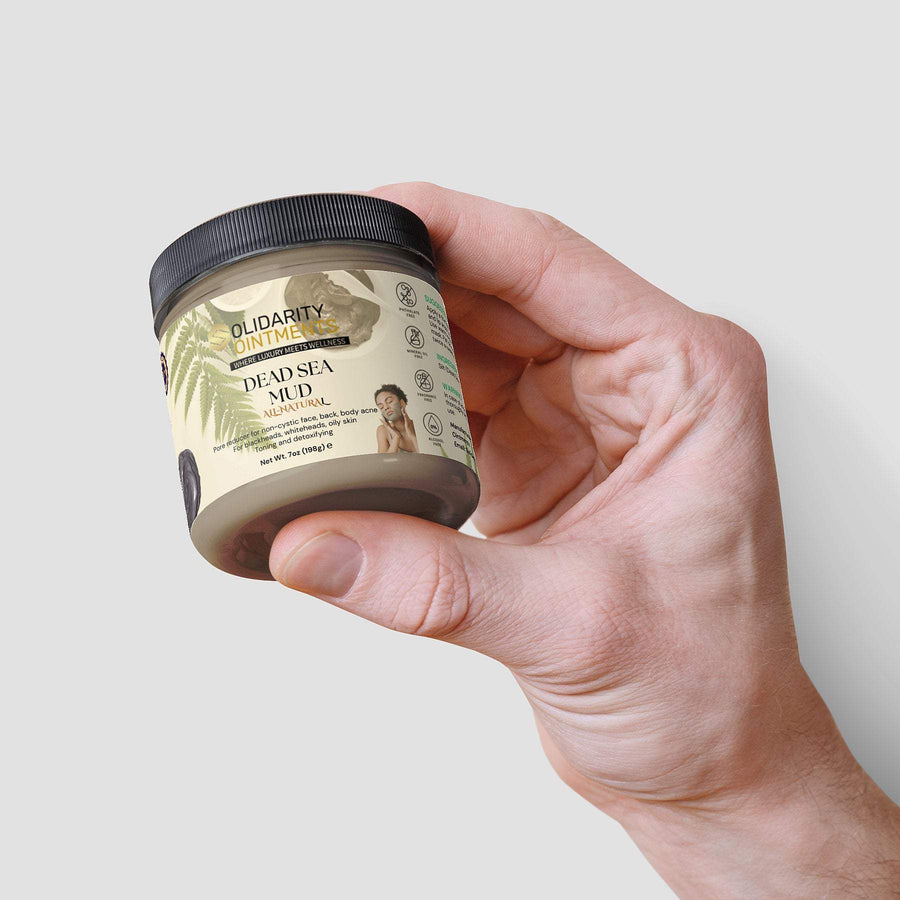 Jar of Dead Sea Mud held in hand, showcasing natural skincare product with mineral-rich formula for revitalizing skin.