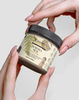 Dead Sea Mud jar held in hands for natural skincare rejuvenation.