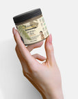 Dead Sea Mud jar held in hand, mineral-rich skincare remedy for rejuvenation and pore reduction.